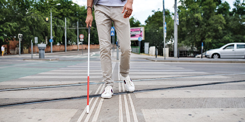 Man with cane walking down road